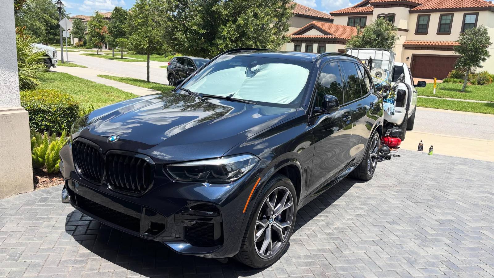 Glossy black BMW X5 freshly detailed by Premier One in a New Port Richey driveway
